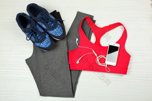 运动服装、 鞋、 带着耳机在浅色背景上的智能手机