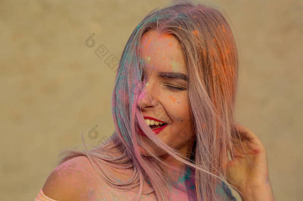 特写肖像的笑金发女郎与红唇玩橙色干漆在沙漠