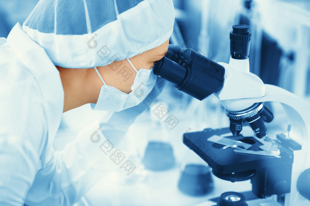 Young woman medical researcher looking through microscop slide in the life science (forensics, micro