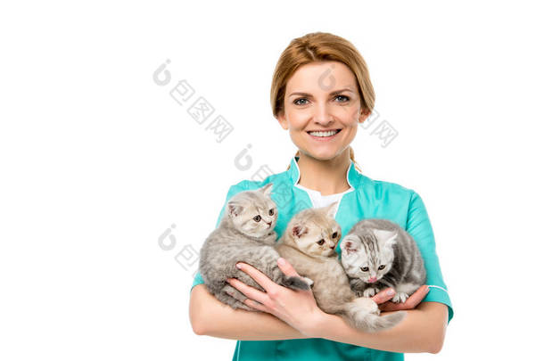美丽的年轻兽医抱着可爱的小猫, 微笑着在白色的相机隔离