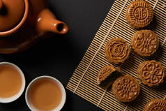 在竹桌垫上可以看到传统月饼、茶壶和杯子的顶视图