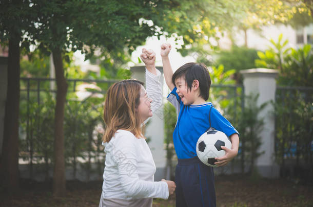亚洲母亲和儿子一起在公园踢足球