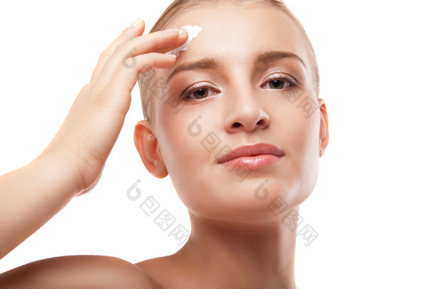 女人在孤立的脸上应用保湿霜