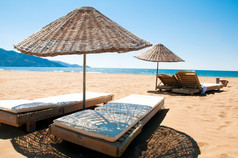 在沙海边的日光浴浴床和藤遮阳伞.