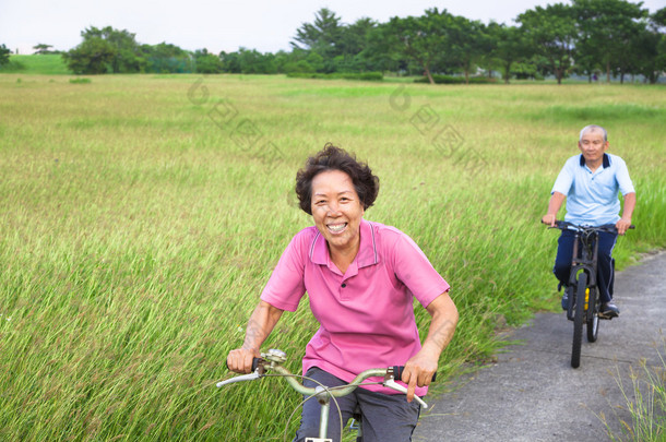 快乐亚洲老年人情侣在公园里骑<strong>自行车</strong>.