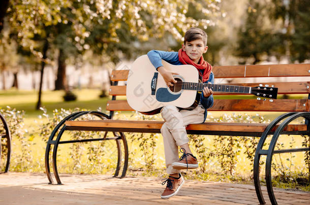 小男孩在公园里弹吉他