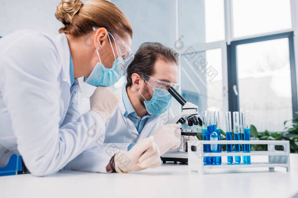 研究人员在白色大衣和医疗口罩一起使用试剂在实验室