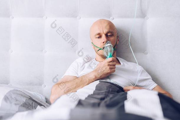 男人在床上通过氧气罩<strong>呼吸</strong>。Covid-19病人.