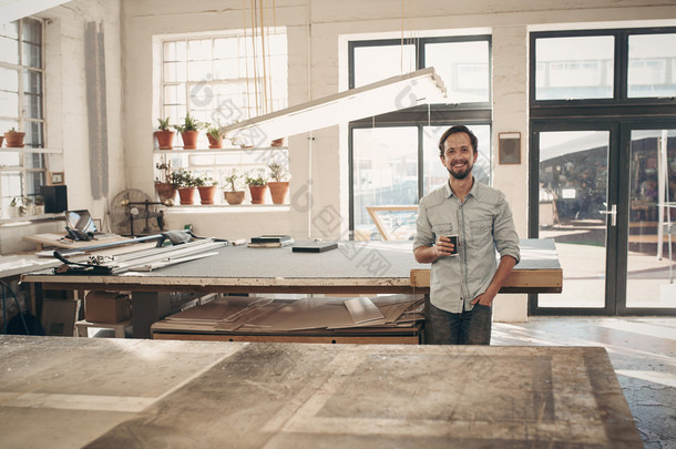 designer standing in workshop with cup of coffee