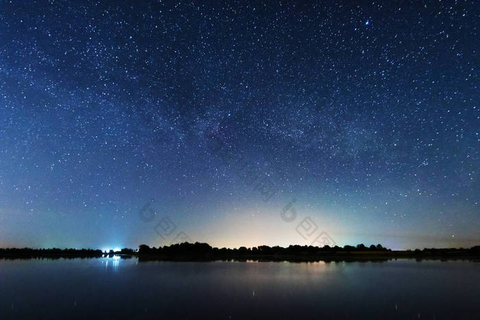 在河岸上的一个迷人的星夜，有一棵大树，天空中的一条银河，夏天有流星坠落.