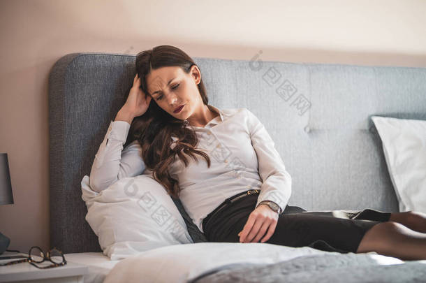 疲倦而沮丧的女商人躺在旅馆的床上.