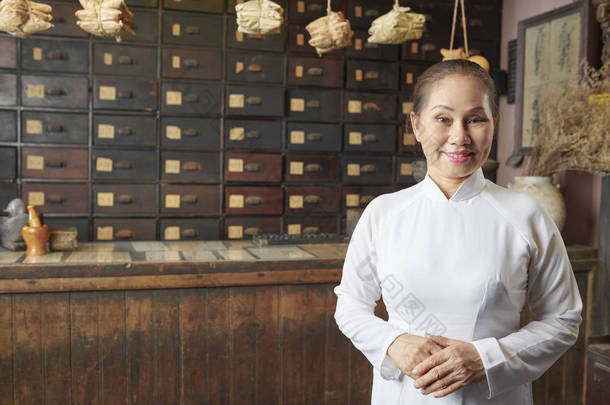 站在中国传统药店前身穿白色传统服装的亚洲女人的画像