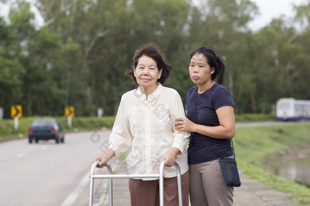 使用<strong>助行器</strong>的高级女子过马路