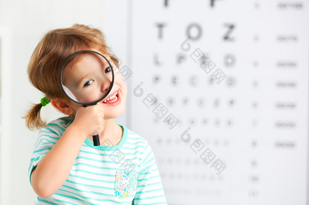 视力测试的概念。儿童女孩用放大镜