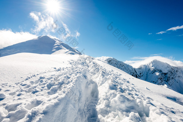 冬天与灿烂的阳光和蓝色的白雪覆盖的山顶