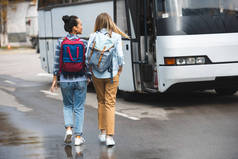 在城市街道的背包步行附近的旅游巴士的妇女后视图