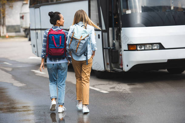 在城市街道的背包步行附近的旅游巴士的妇女后视图