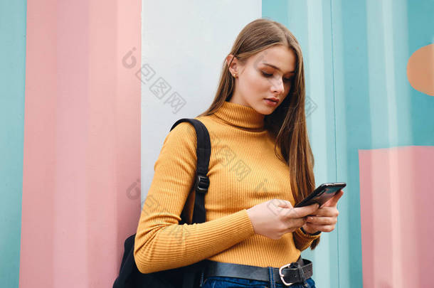 在户外用手机在色彩艳丽的背景下<strong>吸引</strong>那些随和的女生