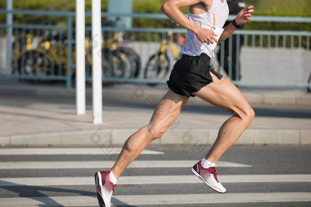 马拉松运动员腿在城市道路上奔跑