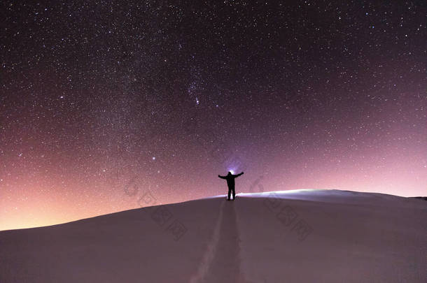 男人用车灯在晚上的雪路的尽头