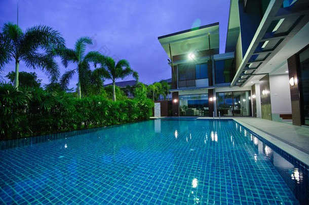 现代的房子，有室外游泳池，在夜间 