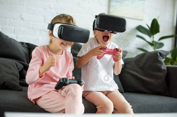小孩子在虚拟现实中的耳机在家里的沙发上玩视频游戏