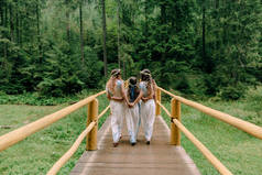 妈妈和两个女儿穿着白色裙子着花环的野花在湖边散步