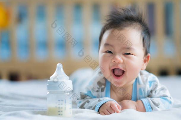 亚洲新生婴儿微笑与电源瓶牛奶