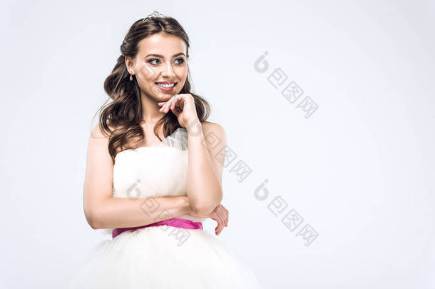 微笑的年轻新娘穿着婚纱看着<strong>远离</strong>孤立的白色