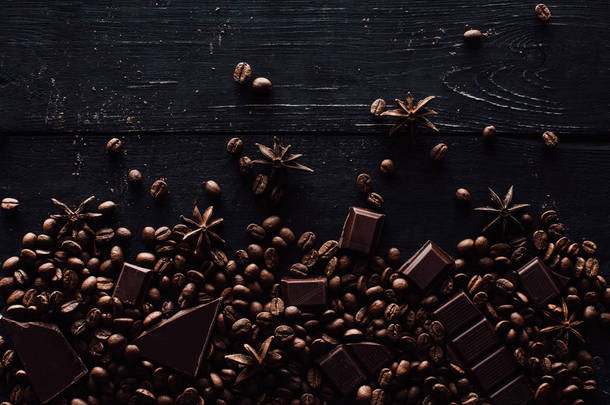 木桌上的八角、巧克力片和咖啡豆堆的高视图