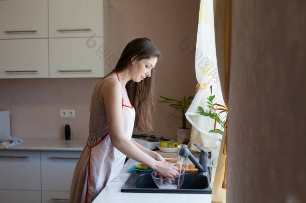 女孩的家庭主妇洗<strong>脏盘子</strong>在厨房里