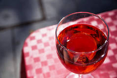 在一个晴朗的晴天, 一杯红酒放在街道咖啡馆的桌子上。