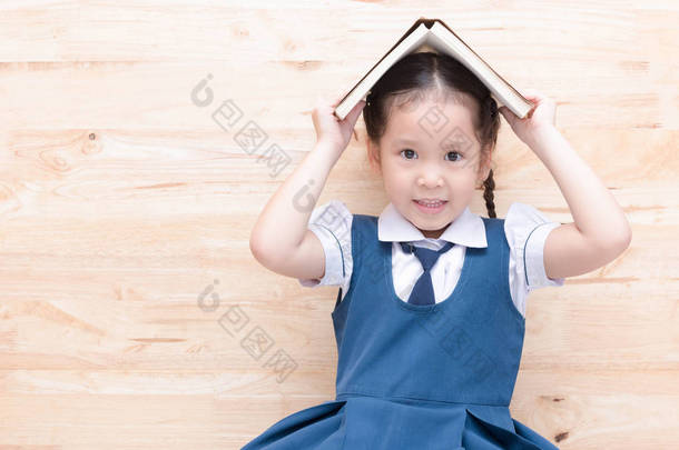 可爱的<strong>亚洲</strong>女孩微笑着头木背景上的书