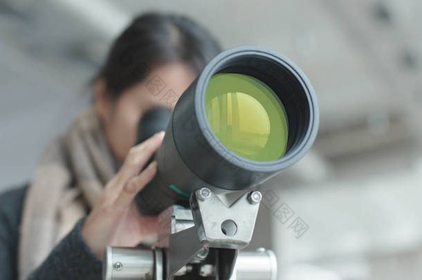 年轻女子通过望远镜观察 