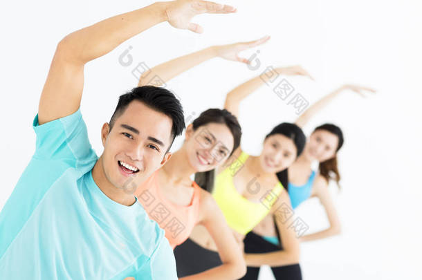 面带笑容的年轻人适合组伸展在健身房