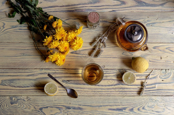 有用的草本茶与植物（西地炎卡）或希腊山茶与柠檬在杯子和黄菊花在木桌特写