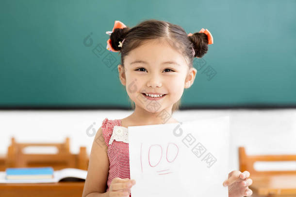 快乐的小女孩在教室里显示一个加号的试卷