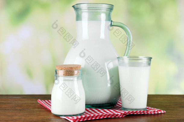 壶、 罐、 杯牛奶在木桌子上，对自然背景