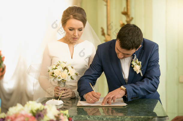 年轻新郎在登记处签署结婚合同的特写