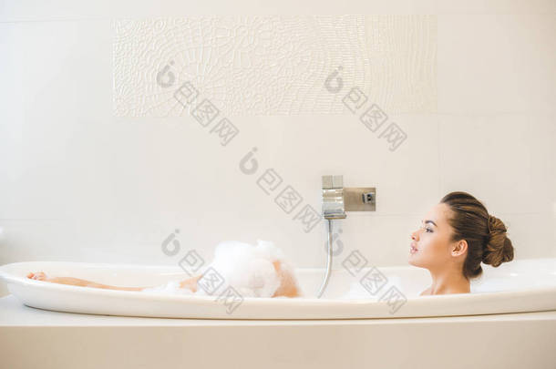 年轻美丽的女人在家里洗澡的侧视图