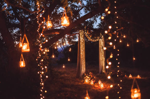 晚上的婚礼上有很多灯, 蜡烛, 灯笼。美丽的浪漫闪亮的装饰在黄昏