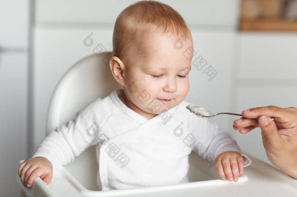 在厨房用<strong>勺子</strong>喂养可爱的婴儿