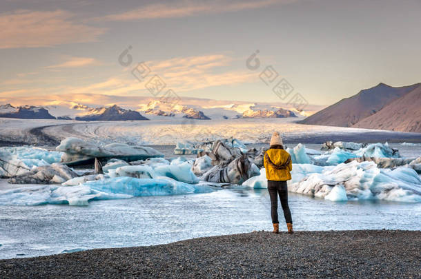 年轻女子穿冷衣服看到惊人的 Jokulsarlon, 冰山泻湖在冰岛