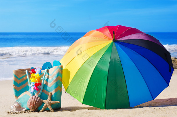 夏天背景与彩虹伞和沙滩袋