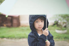 快乐的亚洲男孩抱着五颜六色的伞，公园里玩 