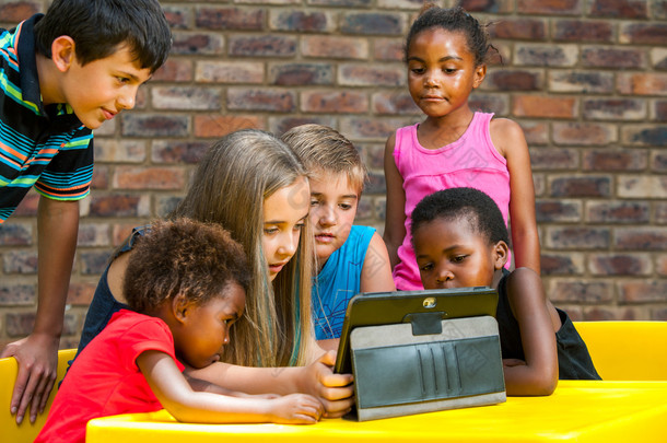 不同群体的孩子们看着平板电脑.