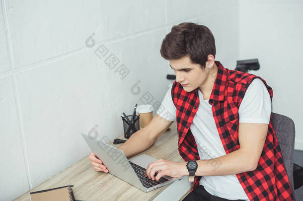 在家使用膝上型电脑的年轻男学生