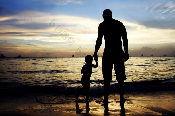 <strong>父亲</strong>和儿子在夕阳的大海和天空背景上