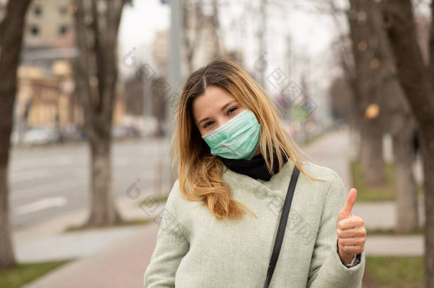 漂亮的姑娘，脸上戴着无菌防护面罩的年轻女子，在欧洲的一个城市里散步，像个手势一样竖起<strong>大拇指</strong>。环境生态污染问题拯救我<strong>们</strong>的地球概念