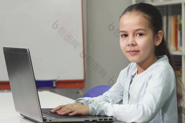 快乐美丽的亚洲小女孩使用笔记本电脑微笑